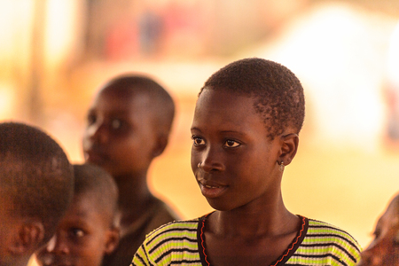 OUIDAH, BENIN - Jan 9, 2017: Unidentified Beninese girl in colored shirt with beautiful eyes. Benin children suffer of poverty due to the bad economyのeditorial素材