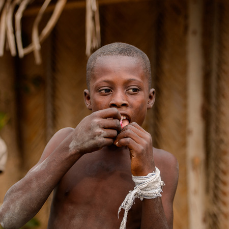 LOME, TOGO - Jan 9, 2017: Unidentified Togolese young boy puts some candy into his mouth. Togo children suffer of poverty due to the bad economyのeditorial素材