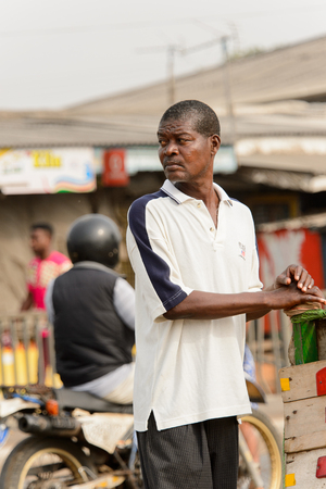 ACCRA, GHANA - Jan 8, 2017: Unidentified Ghanaian man in white shirt with blue stripes looks around. People of Ghana suffer of poverty due to the economic situationのeditorial素材