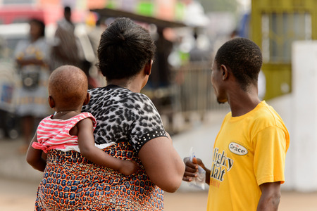 ACCRA, GHANA - Jan 8, 2017: Unidentified Ghanaian woman carries a baby on her back. People of Ghana suffer of poverty due to the economic situationのeditorial素材