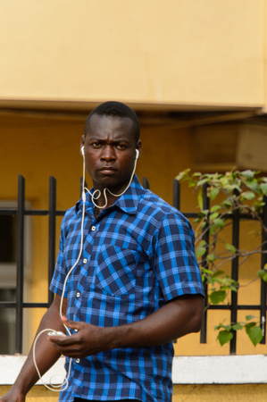 ACCRA, GHANA - Jan 8, 2017: Unidentified Ghanaian man in blue shirt listens to music. People of Ghana suffer of poverty due to the economic situationのeditorial素材