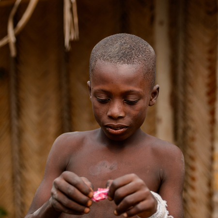LOME, TOGO - Jan 9, 2017: Unidentified Togolese young boy opens a candy. Togo children suffer of poverty due to the bad economyのeditorial素材