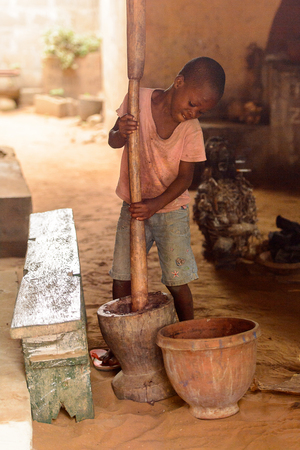 LOME, TOGO - Jan 9, 2017: Unidentified Togolese young boy holds a wooden stick in the local shaman's house. Togo children suffer of poverty due to the bad economyのeditorial素材