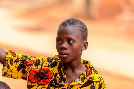 OUIDAH, BENIN - Jan 9, 2017: Unidentified Beninese boy in colored shirt raises his hand. Benin children suffer of poverty due to the bad economyのeditorial素材