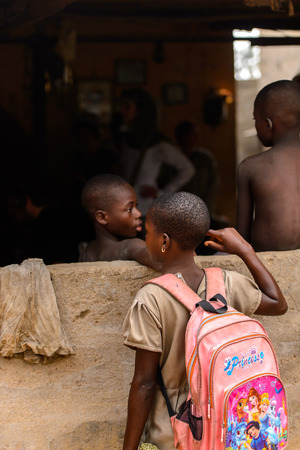 LOME, TOGO - Jan 9, 2017: Unidentified Togolese young girl carries a backpack near the local shaman's house. Togo people suffer of poverty due to the bad economyのeditorial素材