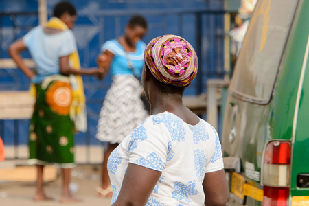 ACCRA, GHANA - Jan 8, 2017: Unidentified Ghanaian woman in white and blue shirt and a hat from behind. People of Ghana suffer of poverty due to the economic situationのeditorial素材