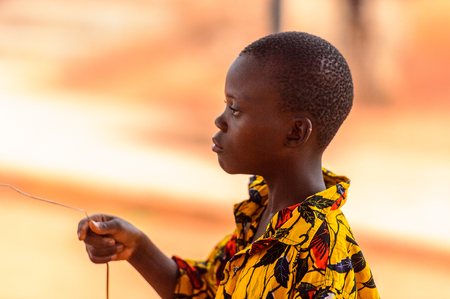OUIDAH, BENIN - Jan 9, 2017: Unidentified Beninese boy in colored shirt raises his arm. Benin children suffer of poverty due to the bad economyのeditorial素材