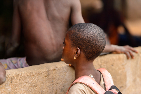 Photo for LOME, TOGO - Jan 9, 2017: Unidentified Togolese young girl carries a backpack near the local shaman's house. Togo people suffer of poverty due to the bad economy - Royalty Free Image