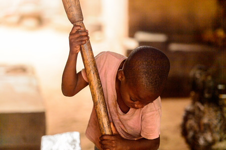 LOME, TOGO - Jan 9, 2017: Unidentified Togolese young boy holds a wooden stick in the local shaman's house. Togo children suffer of poverty due to the bad economyのeditorial素材