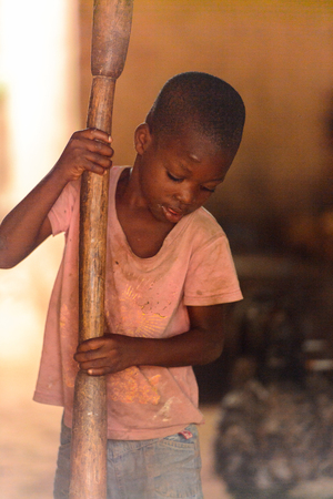 LOME, TOGO - Jan 9, 2017: Unidentified Togolese young boy holds a wooden stick in the local shaman's house. Togo children suffer of poverty due to the bad economyのeditorial素材