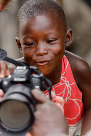 ACCRA, GHANA - Jan 8, 2017: Unidentified Ghanaian little boy looks at photos on camera at the local market. People of Ghana suffer of poverty due to the economic situationのeditorial素材