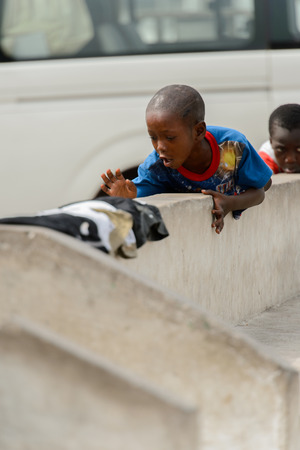 ACCRA, GHANA - Jan 8, 2017: Unidentified Ghanaian boys sit on the fence at the local market. People of Ghana suffer of poverty due to the economic situationのeditorial素材