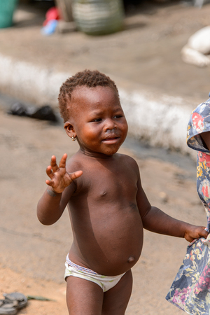 ACCRA, GHANA - Jan 8, 2017: Unidentified Ghanaian little girl waves her hand at the local market. People of Ghana suffer of poverty due to the economic situationのeditorial素材