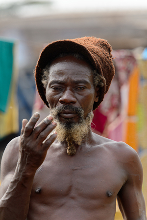 ACCRA, GHANA - Jan 8, 2017: Unidentified Ghanaian hippie man with beard stands at the local market. People of Ghana suffer of poverty due to the economic situationのeditorial素材