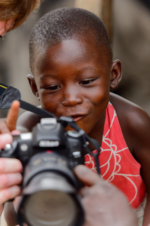 ACCRA, GHANA - Jan 8, 2017: Unidentified Ghanaian little boy looks at photos on camera at the local market. People of Ghana suffer of poverty due to the economic situationのeditorial素材