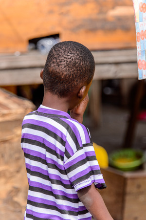 ACCRA, GHANA - Jan 8, 2017: Unidentified Ghanaian boy from behind at the local market. People of Ghana suffer of poverty due to the economic situationのeditorial素材