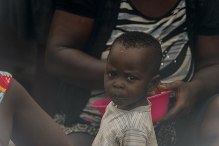 ACCRA, GHANA - Jan 8, 2017: Unidentified Ghanaian little girt with dirty face at the local market. People of Ghana suffer of poverty due to the economic situationのeditorial素材