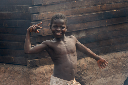 ACCRA, GHANA - Jan 8, 2017: Unidentified Ghanaian topless boy in beige shorts stands at the local market. People of Ghana suffer of poverty due to the economic situationのeditorial素材