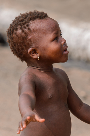 ACCRA, GHANA - Jan 8, 2017: Unidentified Ghanaian little girl looks up at the local market. People of Ghana suffer of poverty due to the economic situationのeditorial素材