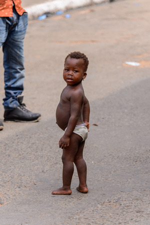 ACCRA, GHANA - Jan 8, 2017: Unidentified Ghanaian little girl looks around at the local market. People of Ghana suffer of poverty due to the economic situationのeditorial素材