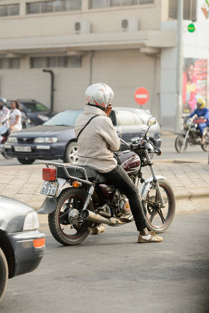 LOME, TOGO - Jan 9, 2017: Unidentified Togolese man in helmet rides a motorcycle. Togo people suffer of poverty due to the bad economyのeditorial素材