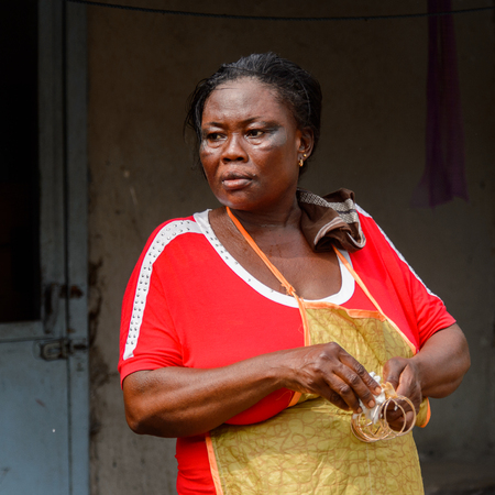 ACCRA, GHANA - Jan 8, 2017: Unidentified Ghanaian woman in red dress looks away at the local market. People of Ghana suffer of poverty due to the economic situationのeditorial素材