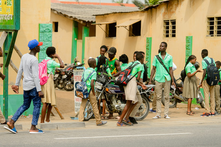 LOME, TOGO - Jan 9, 2017: Unidentified Togolese pupils in school uniform walk on the street. Togo children suffer of poverty due to the bad economyのeditorial素材