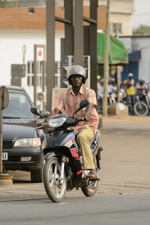 LOME, TOGO - Jan 9, 2017: Unidentified Togolese man in helmet rides a motorcycle. Togo people suffer of poverty due to the bad economyのeditorial素材
