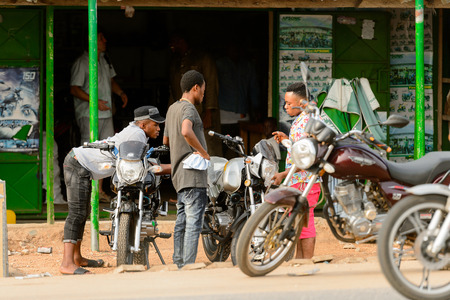 ACCRA, GHANA - Jan 8, 2017: Unidentified Ghanaian boys gather near their motorcycles on the street. People of Ghana suffer of poverty due to the economic situationのeditorial素材