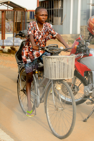 ACCRA, GHANA - Jan 8, 2017: Unidentified Ghanaian woman rides a bicycle on the street. People of Ghana suffer of poverty due to the economic situationのeditorial素材