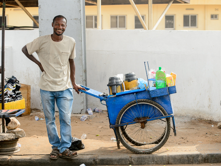 LOME, TOGO - Jan 9, 2017: Unidentified Togolese man in white shirt and jeens with a cart smiles. Togo people suffer of poverty due to the bad economyのeditorial素材