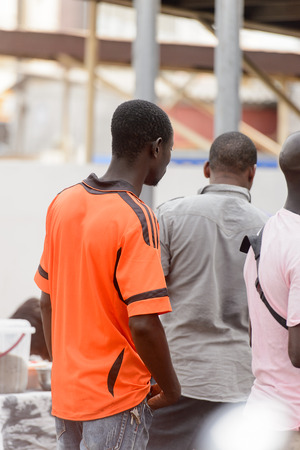 LOME, TOGO - Jan 9, 2017: Unidentified Togolese man in orange shirt with black stripes from behind. Togo people suffer of poverty due to the bad economyのeditorial素材