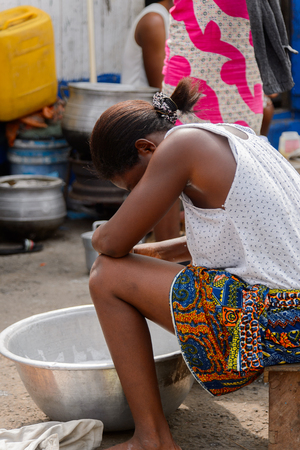ACCRA, GHANA - Jan 8, 2017: Unidentified Ghanaian woman sits on a wooden chair at the local market. People of Ghana suffer of poverty due to the economic situationのeditorial素材