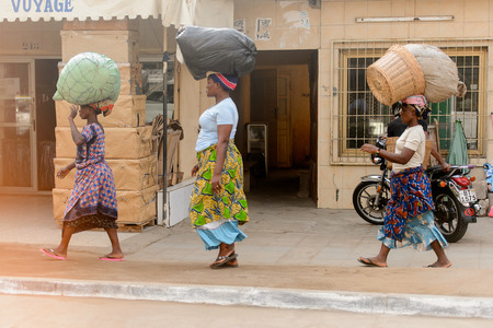 LOME, TOGO - Jan 9, 2017: Unidentified Togolese woman carries a bag on her head. Togo people suffer of poverty due to the bad economyのeditorial素材