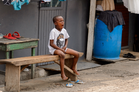 ACCRA, GHANA - Jan 8, 2017: Unidentified Ghanaian little boy yawns at the local market. People of Ghana suffer of poverty due to the economic situationのeditorial素材