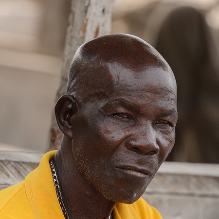 ACCRA, GHANA - Jan 8, 2017: Unidentified Ghanaian serious man in yellow shirt at the local market. People of Ghana suffer of poverty due to the economic situationのeditorial素材