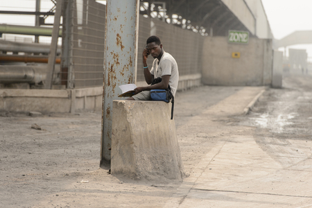 LOME, TOGO - Jan 9, 2017: Unidentified Togolese man listens to music and holds a notebook. Togo people suffer of poverty due to the bad economyのeditorial素材