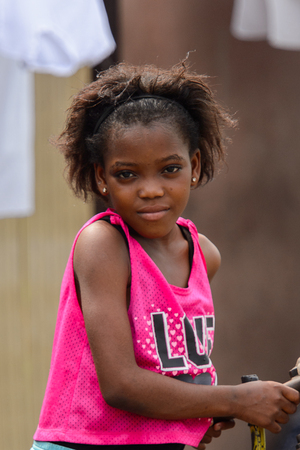 ACCRA, GHANA - Jan 8, 2017: Unidentified Ghanaian beautiful little girl holds her bike at the local market. People of Ghana suffer of poverty due to the economic situationのeditorial素材