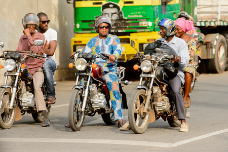 LOME, TOGO - Jan 9, 2017: Unidentified Togolese man in helmet rides a motorcycle. Togo people suffer of poverty due to the bad economyのeditorial素材