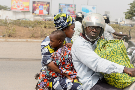 LOME, TOGO - Jan 9, 2017: Unidentified Togolese man in helmet rides a morotcycle. Togo people suffer of poverty due to the bad economyのeditorial素材