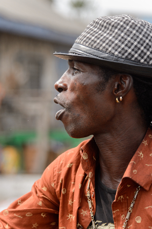 ACCRA, GHANA - Jan 8, 2017: Unidentified Ghanaian stylish man in a hat smiles at the local market. People of Ghana suffer of poverty due to the economic situationのeditorial素材