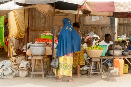 LOME, TOGO - Jan 9, 2017: Unidentified Togolese woman buys fruits and vegetables on the market. Togo people suffer of poverty due to the bad economy.のeditorial素材