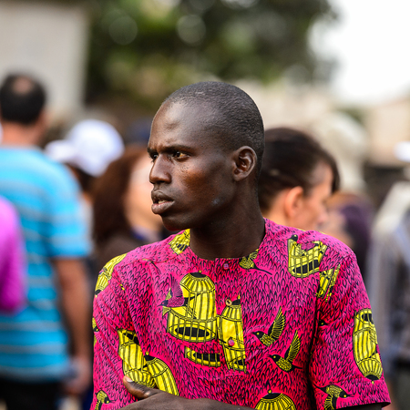 OUIDAH, BENIN - Jan 10, 2017: Unidentified Beninese man in colored shirt seriously looks away at the voodoo festival, which is anually celebrated on January, 10th.のeditorial素材