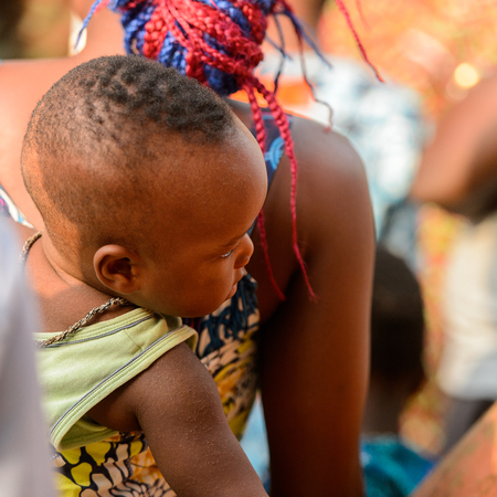 OUIDAH, BENIN - Jan 10, 2017: Unidentified Beninese  little baby carried by his mother on her back...