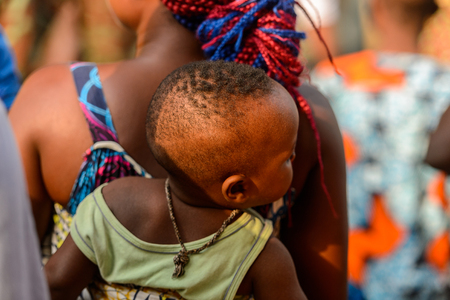 OUIDAH, BENIN - Jan 10, 2017: Unidentified Beninese  little baby carried by his mother on her back at the voodoo festival, which is anually celebrated on January, 10th.のeditorial素材