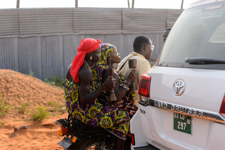 OUIDAH, BENIN - Jan 10, 2017: Unidentified Beninese man rides a motorcycle with another two women at the voodoo festival, which is anually celebrated on January, 10th.のeditorial素材