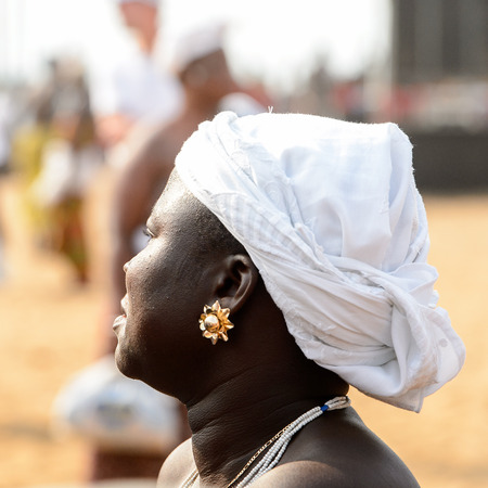 OUIDAH, BENIN - Jan 10, 2017: Unidentified Beninese woman in white headscrarf wears earing at the voodoo festival, which is anually celebrated on January, 10th.のeditorial素材