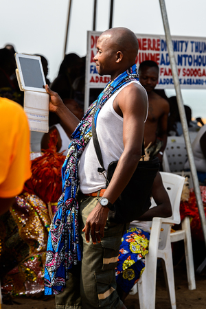 OUIDAH, BENIN - Jan 10, 2017: Unidentified Beninese man shoots something on his tablet at the voodoo festival, which is anually celebrated on January, 10th.のeditorial素材