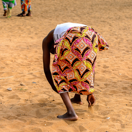 OUIDAH, BENIN - Jan 10, 2017: Unidentified Beninese man in colored clothes collects something in sand at the voodoo festival, which is anually celebrated on January, 10th.のeditorial素材