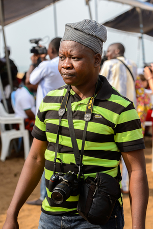 OUIDAH, BENIN - Jan 10, 2017: Unidentified Beninese man in a hat stands with camera at the voodoo festival, which is anually celebrated on January, 10th.のeditorial素材